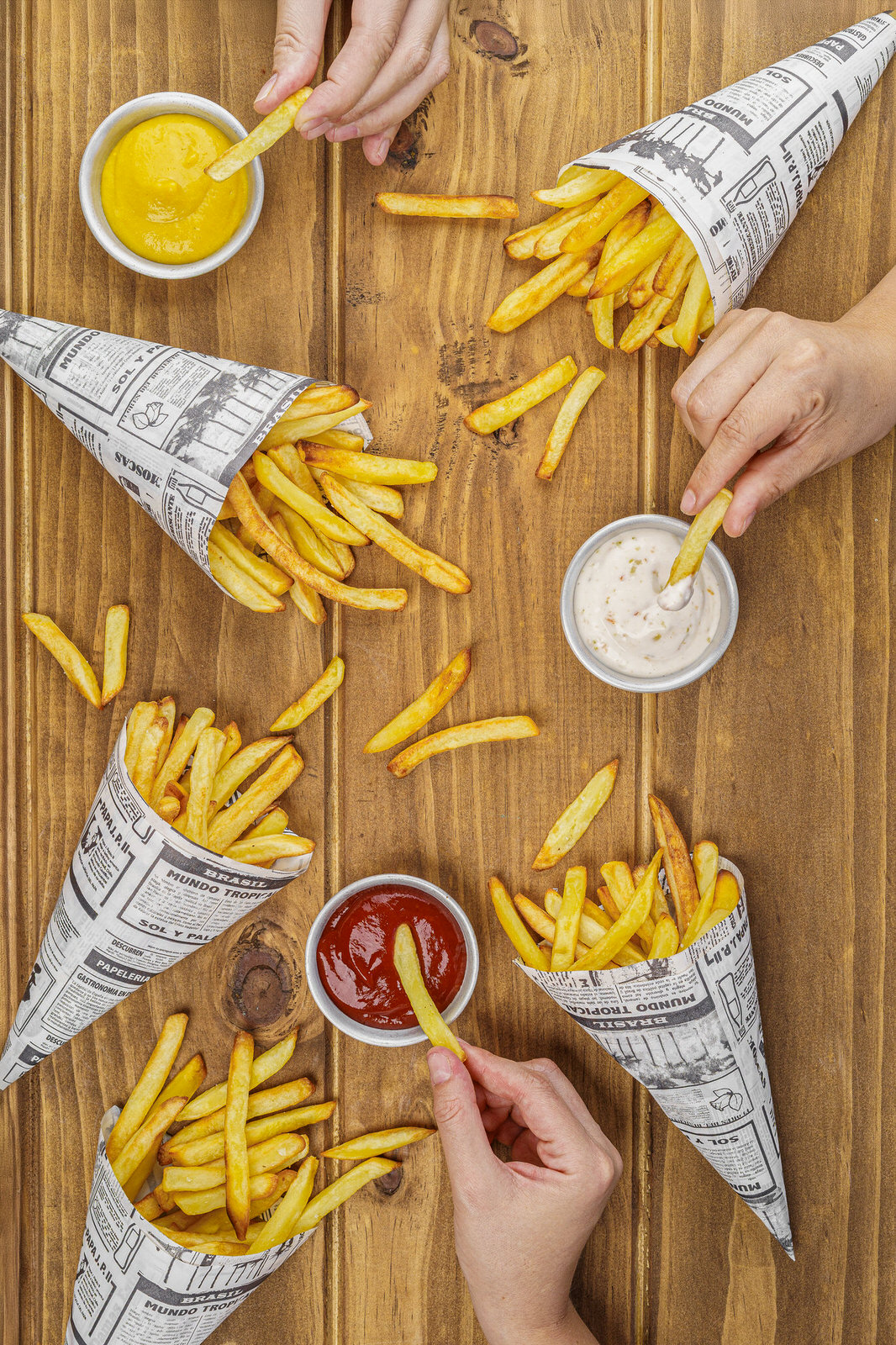Fotografía gastronómica papas fritas manos cenital salsas restaurante
